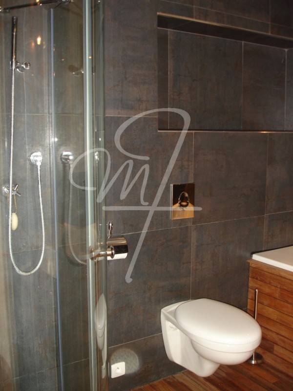 La salle de bains a une fenêtre en double vitrage oscillo-battante et permet une ventilation naturelle. Elle est carrelée jusqu'au plafond. Elle accueille une douche à l'italienne et une baignoire-jacuzzi. Le sol est traité en teck avec joint pont de